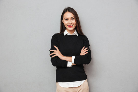 Smiling asian woman in business clothes with crossed arms
