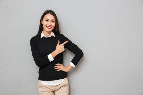 Smiling asian woman in business clothes with arm on hip