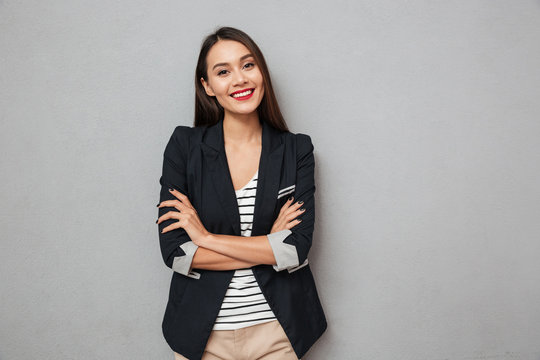 Pleased asian business woman with crossed arms looking at camera