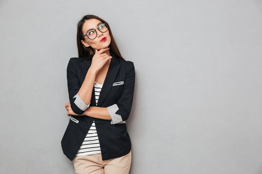 Picture of Pensive asian business woman in eyeglasses looking up