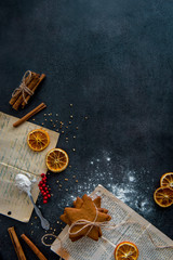 Food preparation. Old recipe, baked gingerbread cookies and ingredients (cinnamon sticks, dried orange slices) on dark modern table from above. Top view, dark background.