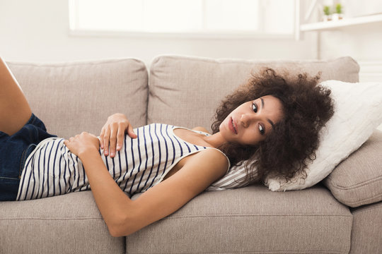 Sad african-american woman on couch at home
