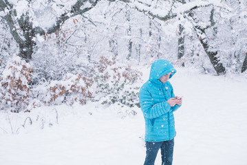 Fototapeta na wymiar teenager with smartphone and blue jacket, snow day