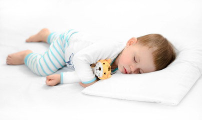 Sleeping baby on white background. Toddler boy in pijama sleeps on white pillow under blanket