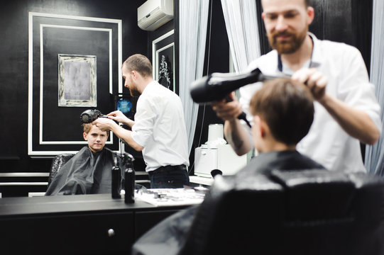 Master cuts hair of a boy in the barbershop, hairdresser makes hairstyle for a boy