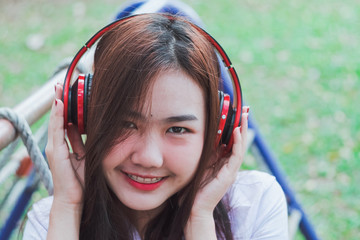 Lady listening music from smart phone with headphones outdoor at a park.