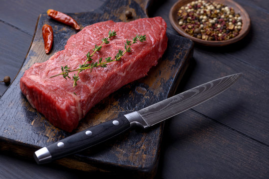 Raw steak with thyme and pepper and knife