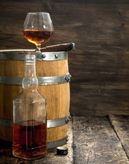 glass of cognac with a cigar on a barrel.