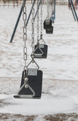 Empty swings in a snowy day in playground