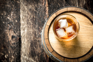 Fototapeta na wymiar glass of Scotch whiskey with a barrel.