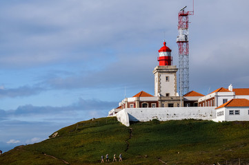 Famous lighthouse, which is located on a green hill. Cabo da Roca (Cape of Roca), Sintra, Portugal