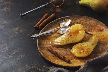 Pear baked in sweet syrup served on a wooden plate. Pear poached.