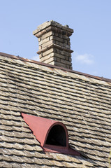 The dominance of the chimney above the old roof. The chimney is built of raw bricks. Landscaped roof disrupted the work of ventilation. The metal borders give the compactness to the roof. 