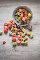Still life of festive mood. Multicolored popcorn in a porcelain bowl on a wooden background