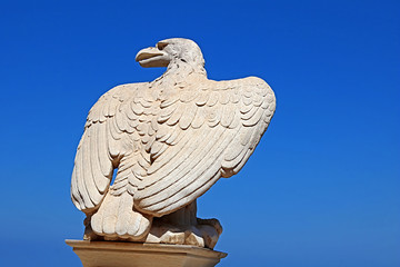 White stone eagle guards the gate to Bahai Gardens over blue sky in Haifa, Israel