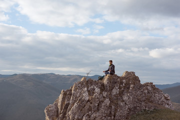 The man meditates in nature after a walk in the hills in the winter