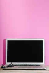 Laptop on desk with pink wall