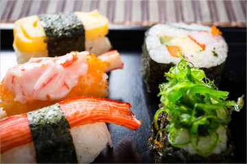 Close up Sushi set with chopsticks and soy on black plate and bamboo background.