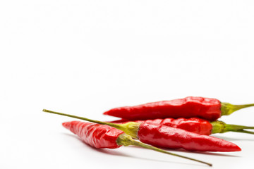 Red chilli peppers are laid on white background.