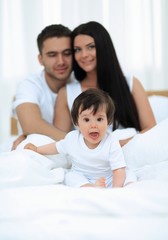 Obraz premium Portrait of a joyful family sitting on the bed at home