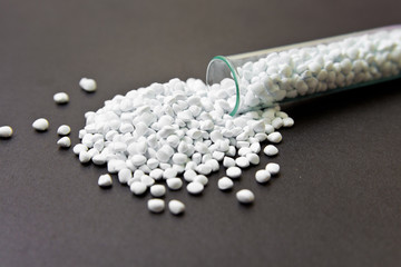 Fototapeta na wymiar Plastic pellets. White Colorant for plastics, in test-tube against a dark background. Plastic Raw material .