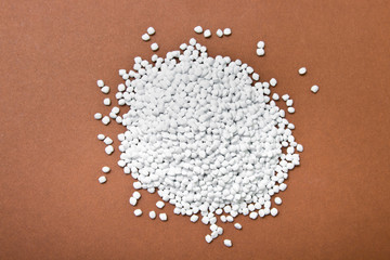 Plastic pellets. White Colorant for plastics on a brown background. Plastic Raw material .