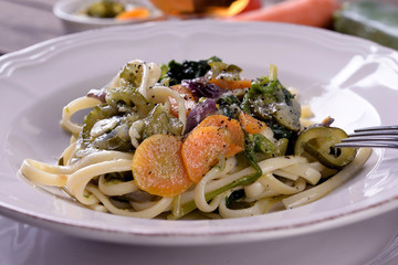 Plate of vegetarian pasta with carrot and zuccini spinach