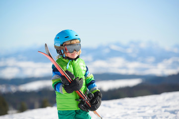 Fototapeta na wymiar Happy skier boy has fun in the mountains on a sunny day