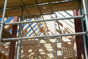 House being built with wooden structure - surrounded by scaffolding