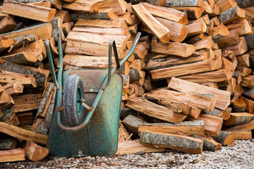 A wheelbarrow near a pile of firewood