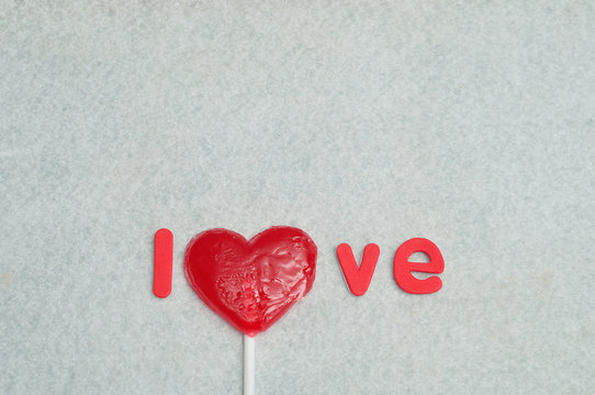 A heart shape lollipop replacing the letter o in the word love