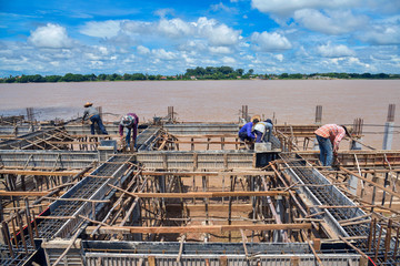 Workers are building a riverfront building.