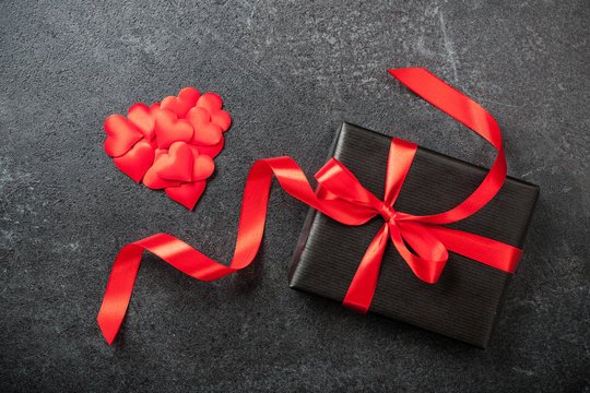Gift box and heart decoration on black background