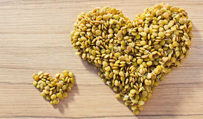 Big and small heart from lentil on wood background, health food concept, legume