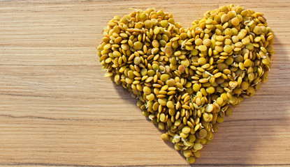Heart from lentil on wood background, health food concept, legume
