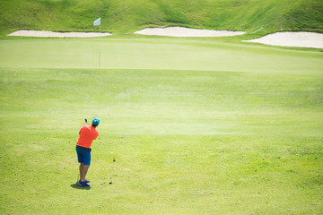 Obraz premium Golfer hitting golf shot with club on course while on summer vacation,Man playing golf on a golf course in the sun