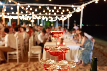 Pyramid from glasses of red wine on wedding party. Close-up of the pink champagne or wine pyramid in ceremony party.