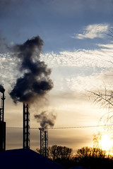 Smoking pipes of thermal power plant on sunset. Concept of bad ecology, air pollution, winter heating, factory production