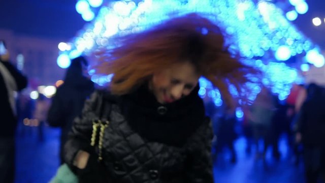Crazy happy curly red hair girl dancing at winter holiday city