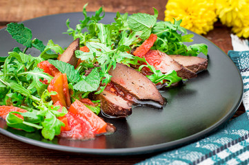 Warm salad, Duck with arugula, tasty, fashionable food, new dish serving. Wooden rustic background. Top view