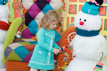 A girl is sitting in an armchair with snowmen in the mall