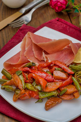 Jamon with grilled vegetables. Spanish cuisine. Wooden rustic background. Top view