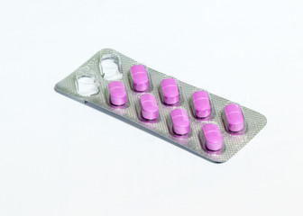 One  open package of pink oblong pills isolated on a white background