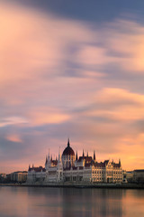 View of the parliament on the Danube river with romantic clouds during sunrise