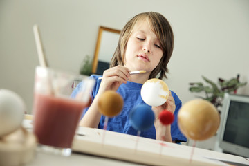 Happy School Boy making a solar system for a school science project at home © mvc_stock
