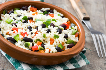 Traditional cuban rice, black beans and pepper on wooden table background. Moros y cristianos.