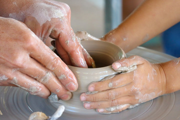 An old hand teching and helps a child to making a vase pottery.
