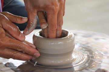 An old hand help and teching a kid to making a vase pottery together.