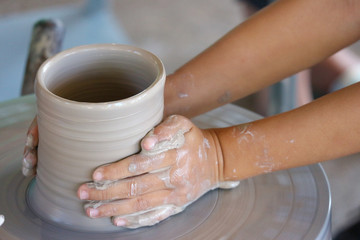 a kid hands making a vase pottery after got teaching from the old hand.