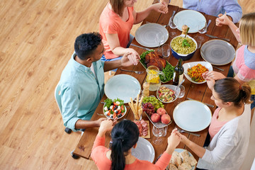 group of people at table praying before meal